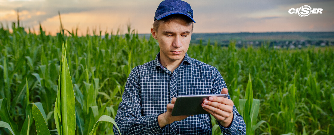 Homem com dispositivo tecnológico para organizar o dia de trabalho no campo.